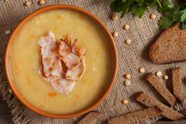 Pea soup yellow traditional homemade recipe with bacon, greens and croutons on vintage wooden table background. National german food. — Stock Photo, Image