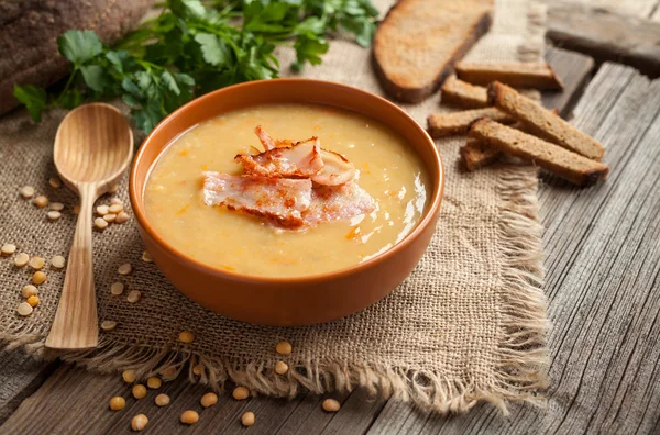 Traditional german homemade pea soup preparation recipe with bacon greens and croutons in clay dish on vintage wooden table background. Tasty national food. — ストック写真