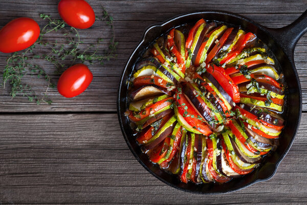 Vegetable ratatouille baked in cast iron frying pan homemade preparation recipe healthy diet french vegetarian food on vintage wooden table background. Top view.