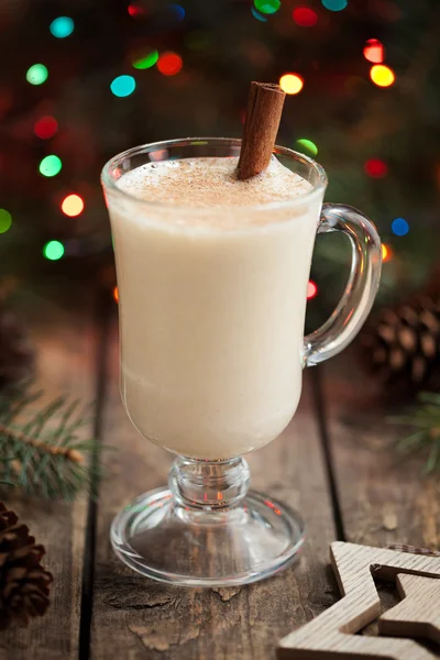 Eggnog christmass holiday traditional celebration milk cream drink in glass cup on vintage wooden table. Colorful bokeh and shallow depth of field. — Stock fotografie