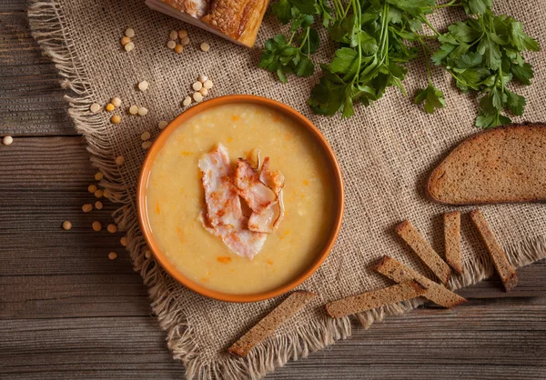 Pea soup traditional German dinner foood with greens, bacon and croutons in clay dish on vintage wooden table background — Stock Image Pea soup traditional German dinner foood with greens, bacon and croutons in clay dish on vintage wooden table background Royalty Free Stock Photos