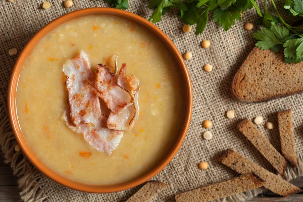 Tasty pea soup yellow traditional homemade food with bacon and croutons on vintage wooden table background — Stock Image Tasty pea soup yellow traditional homemade food with bacon and croutons on vintage wooden table background Royalty Free Stock Photos
