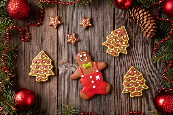 Christmas gingerbread man, stars and fur trees cookies composition in xmas decorations frame on vintage wooden background. Top view. Traditional homemade holiday celebration recipe. — 图库照片