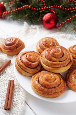 Cinnamon bun rolls christmas sweet dessert on white vintage table with new year decorations. Traditional swedish kanelbullar baked pastry.