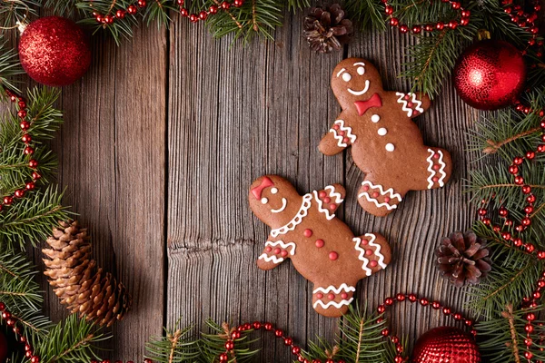 Gingerbread man and woman couple cookies christmas composition in new year tree decorations frame on vintage wooden table background. Top view. Traditional homemade holiday recipe. — 图库照片