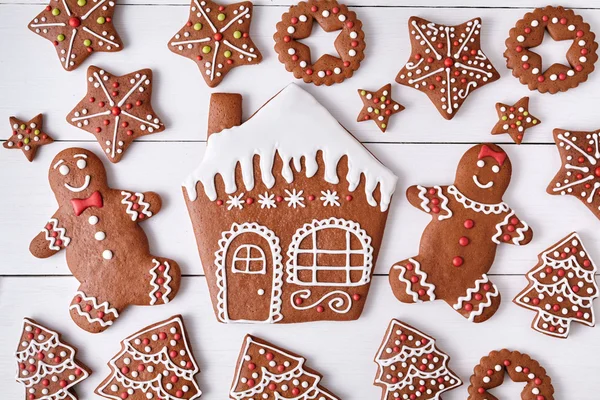 Gingerbreand cookies christmas composition, house man and woman couple, stars, fur trees on white wooden table background. New year traditional dessert food. Top view. — 图库照片