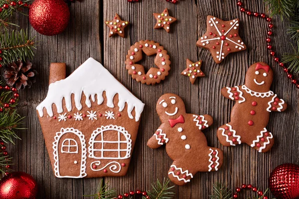 Gingerbread house, man and woman couple, stars christmas cookies with new year tree decorations frame on vintage wooden table background. Traditional homemade celebration recipe. — Stock Fotó