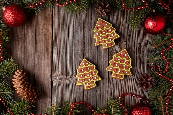 Gingerbread fur trees cookies christmas composition in new year tree decorations frame on vintage wooden table background. Top view. Traditional homemade holiday recipe. — Zdjęcie stockowe