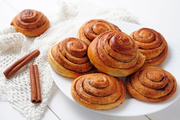 Sweet cinnamon bun rolls christmas delicious dessert on white vintage table. Traditional swedish kanelbullar baked pastry. — Zdjęcie stockowe