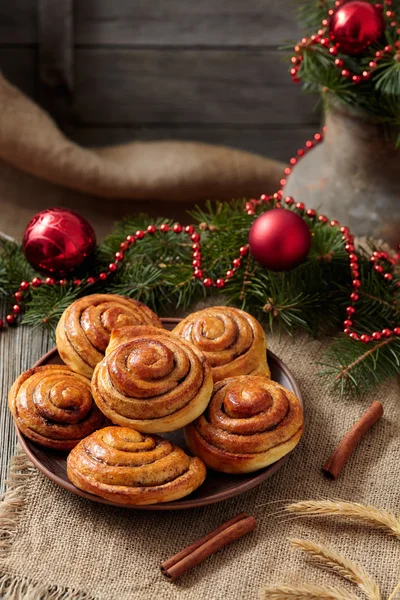 Cinnamon bun rolls christmas sweet dessert on vintage cloth with new year decorations. Traditional swedish kanelbullar baked pastry. — Stock Fotó