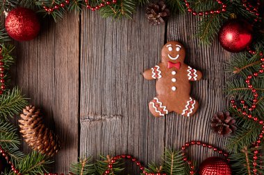 Christmas gingerbread man cookie composition in fir tree decorations frame on vintage wooden table background. Traditional homemade dessert recipe.