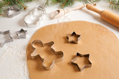 Gingerbread cookies dough preparation recipe with cinnamon rolling pin and flour on white kitchen table. Traditional homemade christmas dessert.
