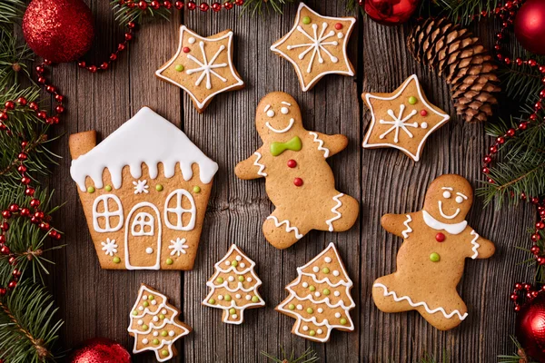 Gingerbread man and woman, house, fir trees, stars cookies composition with christmas decorations on vintage wooden table background. Homemade traditional recipe. — Zdjęcie stockowe