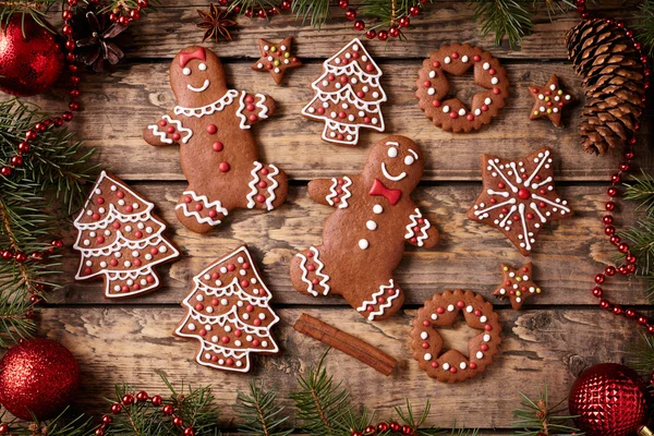 Gingerbread man and woman, fir trees, stars cookies christmas composition in new year decorations frame on vintage wooden table background. Top view. Homemade traditional recipe. — Stock Photo, Image