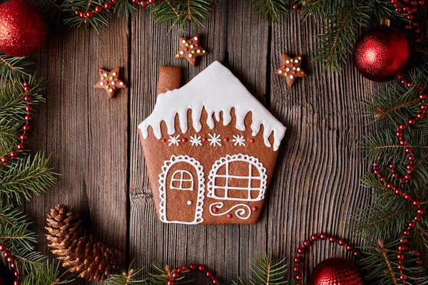 Gingerbread house with stars cookies christmas composition in new year decorations frame on vintage wooden table background. Homemade traditional dessert icing recipe. Top view. — Stock Photo, Image