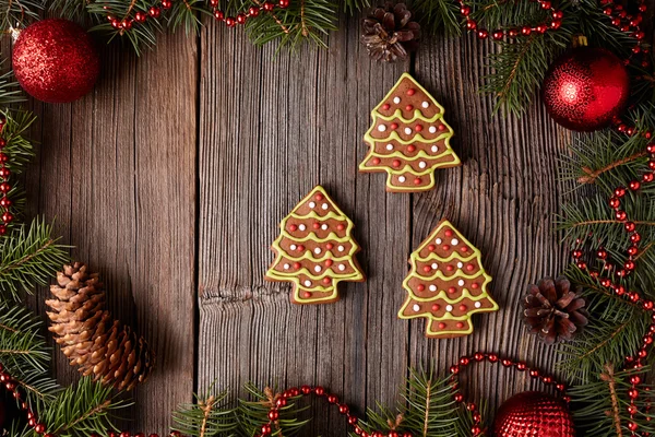 Christmas gingerbread fir trees cookies composition in christmas decorations frame on vintage wooden table background. Traditional homemade dessert recipe. — Zdjęcie stockowe