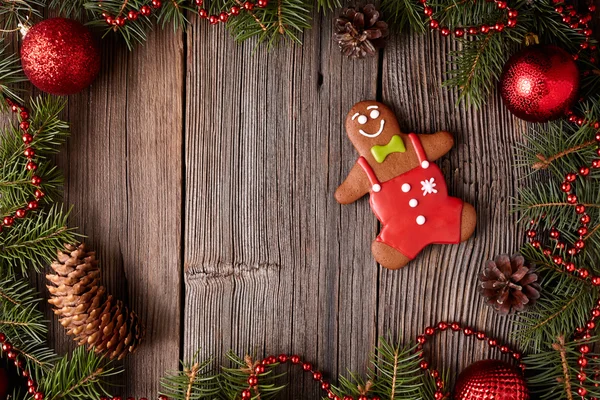 Gingerbread man cookie composition in fir tree decorations frame on vintage wooden table background. Traditional homemade dessert recipe. — Stock Photo, Image