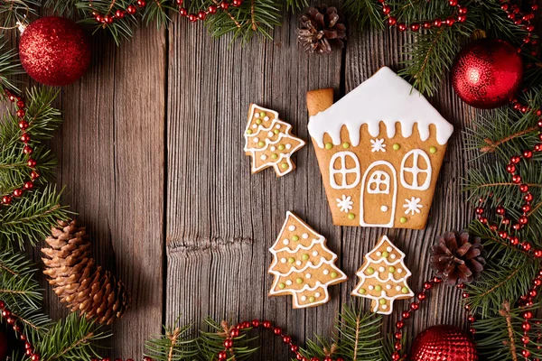 Gingerbread house and fir trees cookies composition with christmas decorations on vintage wooden table background. Homemade traditional recipe. — Stock Photo, Image
