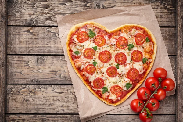 Herzförmige Pizza Margherita mit Tomaten und Mozzarella vegetarische Mahlzeit auf vintage Holztischhintergrund. Essenskonzept der romantischen Liebe zum Valentinstag. — Stockfoto