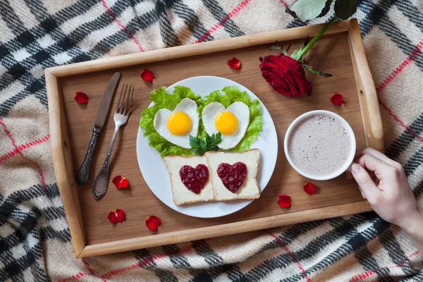 Valentines day breakfast in bed with heart-shaped eggs, jam toasts, coffee, rose flower and petals. Romantic surprise. — Stock Image Valentines day breakfast in bed with heart-shaped eggs, jam toasts, coffee, rose flower and petals. Romantic surprise. Royalty Free Stock Photos