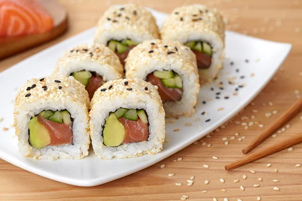 California roll sushi comida tradicional de arroz japonés con salmón, aguacate, pepino, nori y semillas de sésamo . — Foto de Stock