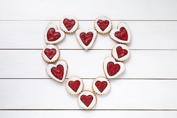 Heart of the shortbread heart-shaped cookies with jam on white wooden table background. — Stok fotoğraf