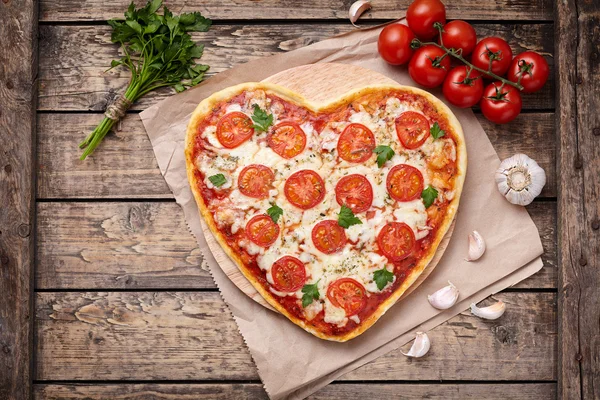 Herzförmige Pizza Margherita vegetarisches Liebeskonzept mit Mozzarella, Tomaten, Petersilie und Knoblauch auf altem Holztischhintergrund — Stockfoto