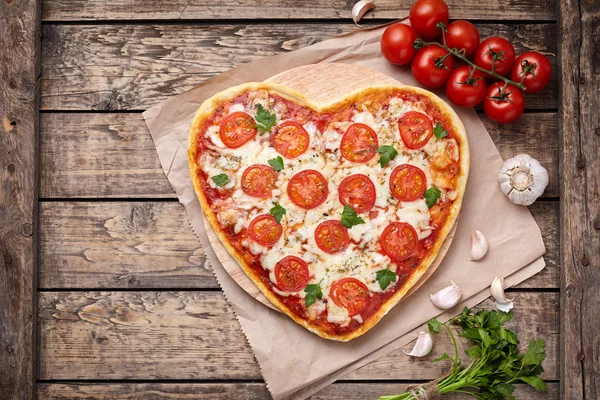 Heart shaped pizza margherita vegetarian love concept with mozzarella, tomatoes, parsley and garlic composition on vintage wooden table background. — Stok fotoğraf