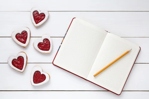 Heart shaped cookies with empty notebook frame and pencil composition for Valentines Day — Zdjęcie stockowe