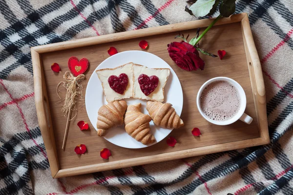 Romantic breakfast in bed for Valentines Day. Toasts with jam, croissants, hot chocolate, red rose flower and petals — Stock Image Romantic breakfast in bed for Valentines Day. Toasts with jam, croissants, hot chocolate, red rose flower and petals Stock Image