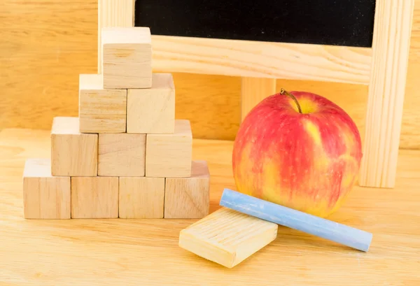 Close up red apple and wood cube in pyramid alignment with chalk — Stock Photo, Image