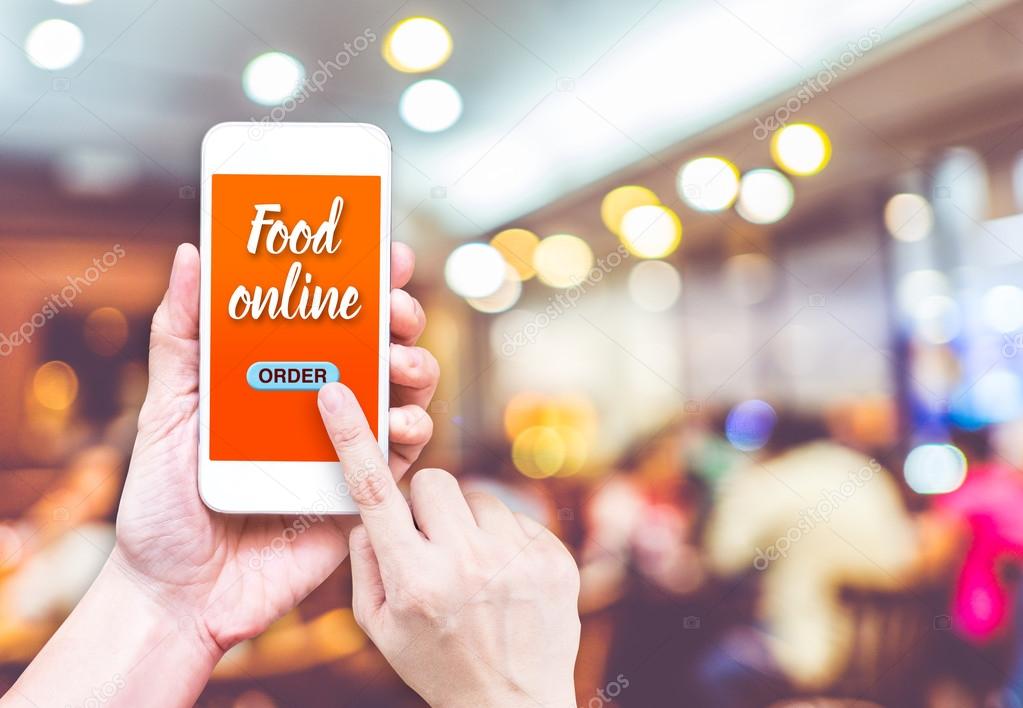 Hand holding mobile with Order food online with blur restaurant 