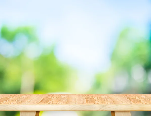 Tampo de mesa de madeira marrom moderno vazio com sol e borrão árvore verde b — Fotografia de Stock