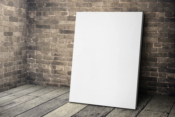 Blank vit canvas ram lutande på grunge tegelvägg och trä f — Stockfoto