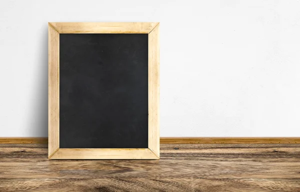 Töm Blackboard lutande på rustika trägolv och vita väggen, — Stockfoto