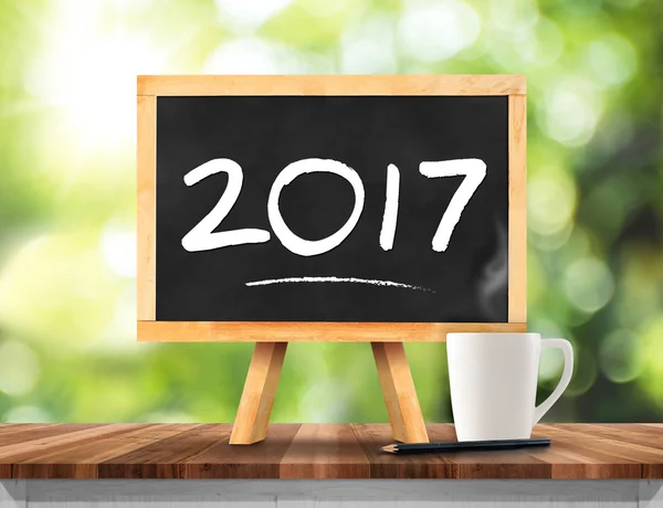 2017 new year on blackboard with coffee cup,pencil on plank wood — Stock Photo, Image
