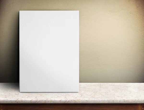 Cartel de papel blanco en blanco sobre mesa de mármol en la pared de hormigón amarillo — Foto de Stock