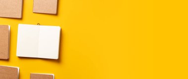 content marketing concept,.top view of hand writing on open notebook align with kraft paper book in pattern on yellow table background.mockup for advertise content online