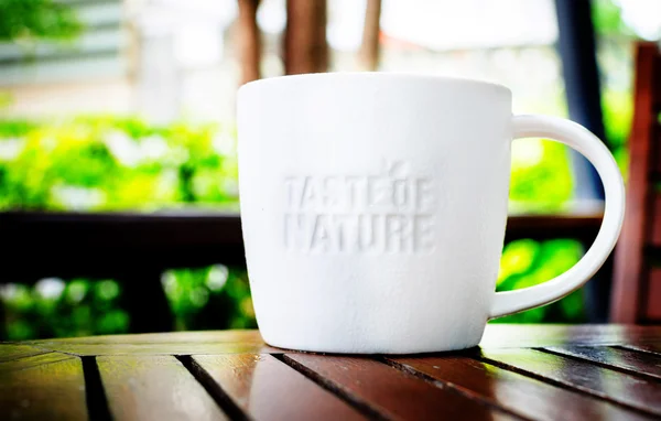 White ceramic mug with stamp word "Taste of nature" at coffee sh — Stock Photo, Image