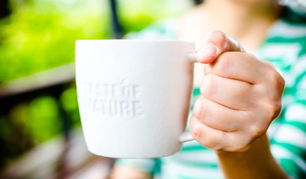 Hand holding White ceramic mug with stamp word "Taste of nature" — Stock Photo, Image