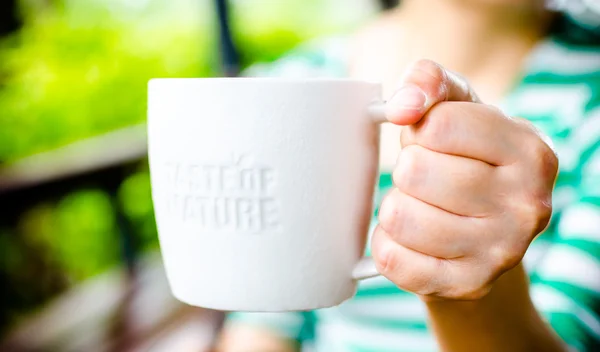 Hand holding White ceramic mug with stamp word \