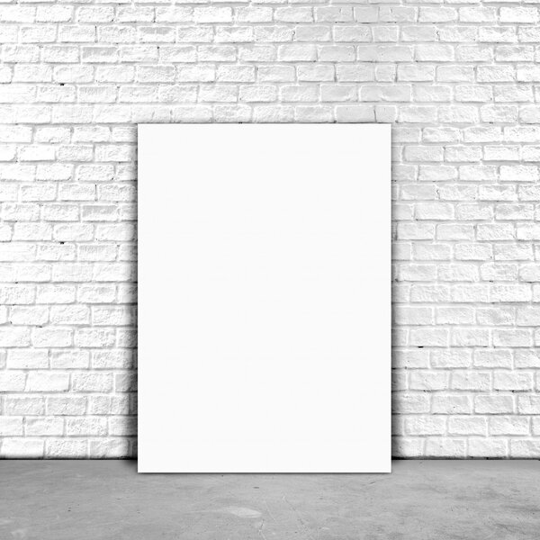 Blank Poster paper standing next to a white brick wall.