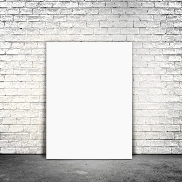 Papel póster en blanco de pie junto a una pared de ladrillo blanco — Foto de Stock