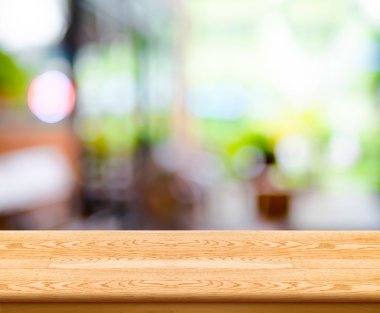 Empty wood table top with coffee shop blur with bokeh background clipart