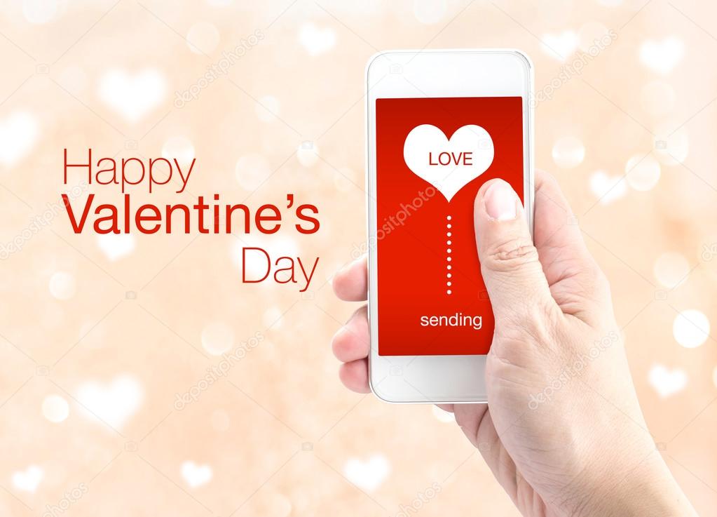 Hand holding smartphone with sending word and heart shape on scr