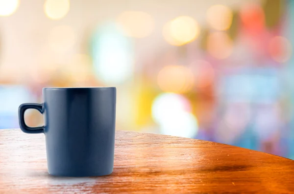 Koffiekopje op houten tafel in bokeh achtergrond wazig — Stockfoto