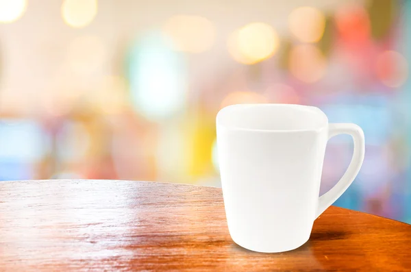 Кофейная чашка на деревянном столе на фоне размытого боке — стоковое фото