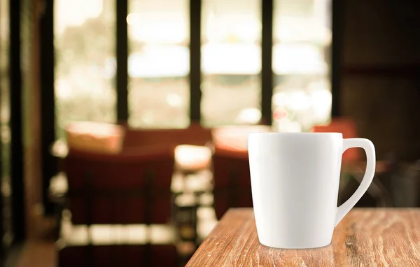 Coffee cup on wood table in blur cafe background — Stock Photo, Image