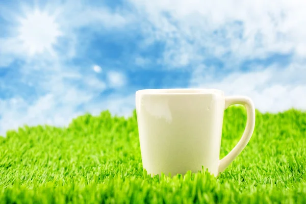 Taza de café blanco sobre hierba verde — Foto de Stock