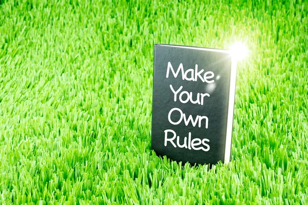 Shining Black book on grass with " Make your own rules " word, B — Stock Photo, Image